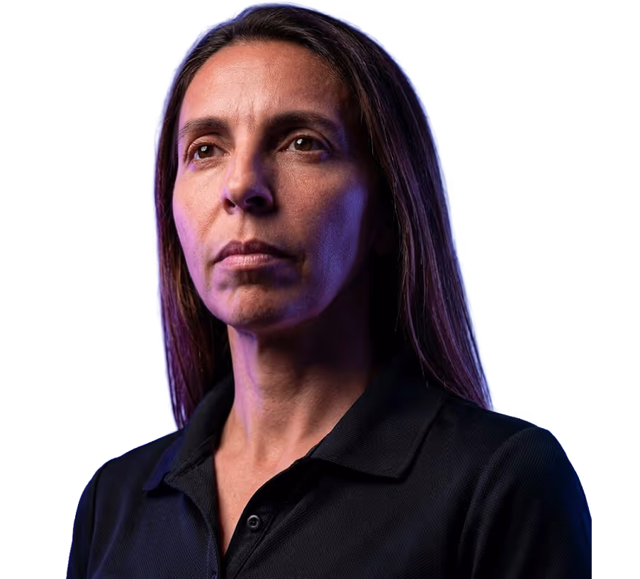 Serious woman with long dark hair wearing a black collared shirt against a blue background.